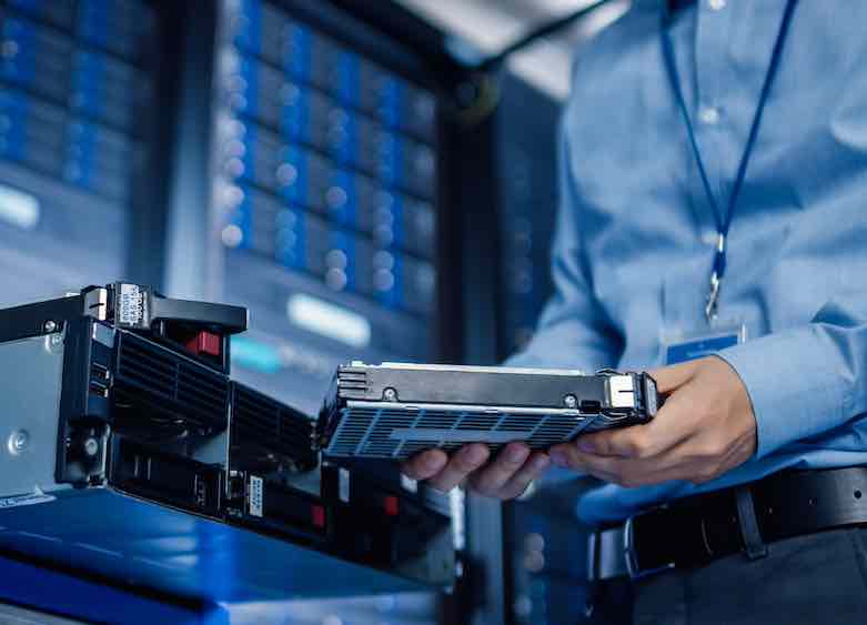 IT Engineer is Holding New HDD Hard Drive Prepared for Installing Hardware Equipment into Server Rack.